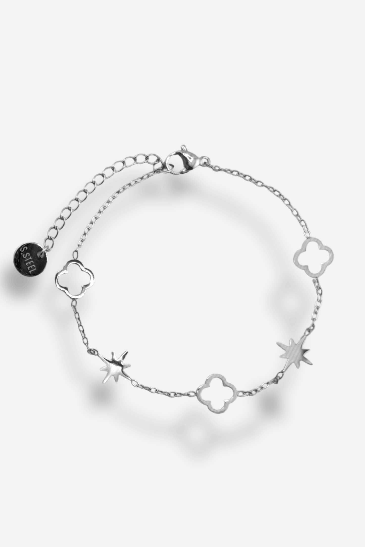 Bracelet en acier inoxydable avec étoiles et trèfles, ajustable grâce à une chaînette d’extension. Disponible en doré ou argenté.