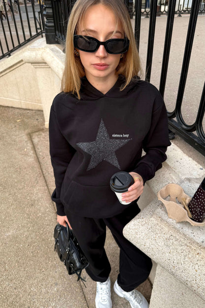 Hoodie noir femme Sisters Bay, broderie argentée premium et capuche. Sweat écoresponsable avec poche kangourou + rangement téléphone. Mode, confort, qualité.