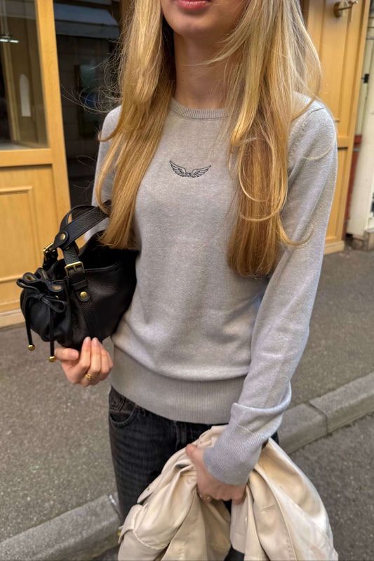 Pull ANGEL gris col rond création exclusive Sisters Bay, coupe ajustée, avec logo blanc ailes d’ange brodé dans notre atelier. Modèle élégant et confortable pour un look quotidien.