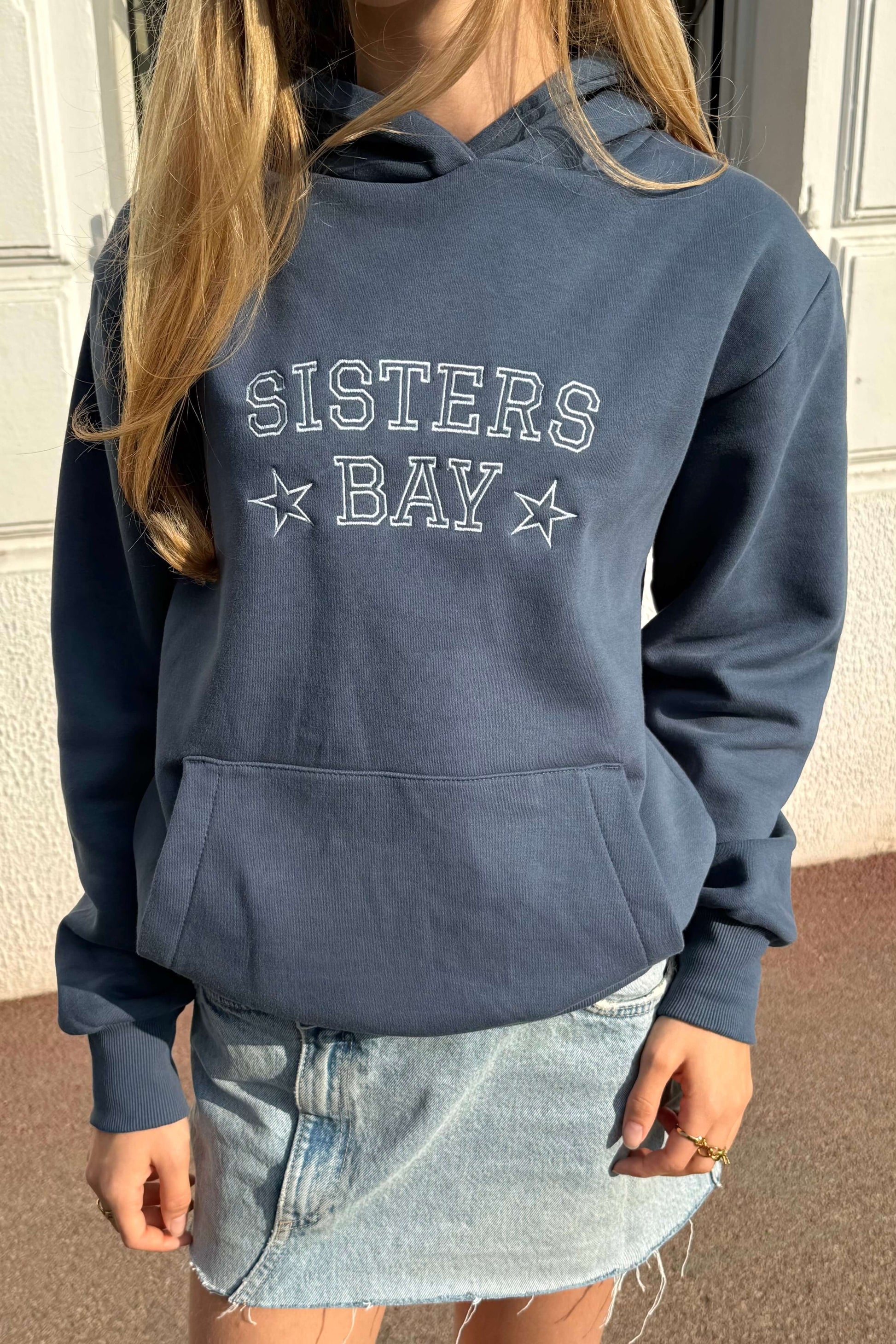 Détail de la broderie bleu clair sur le sweat-shirt Sisters Bay, coupe classique unisexe, coton ringspun et polyester recyclé.