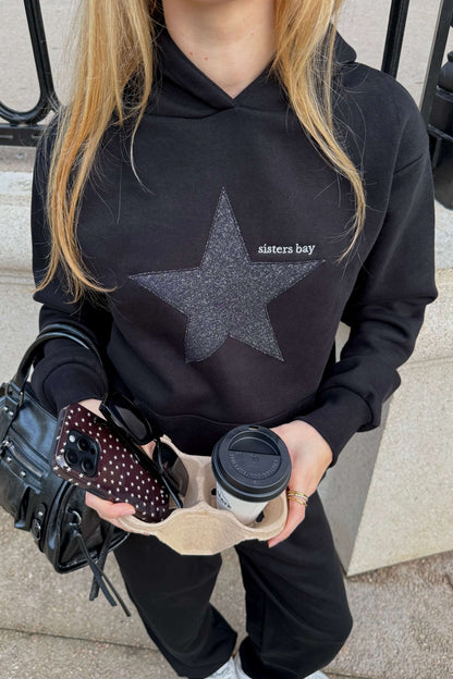 Hoodie noir femme et adolescente Sisters Bay, broderie argentée premium et capuche. Sweat écoresponsable avec poche kangourou + rangement téléphone. Mode, confort, qualité.