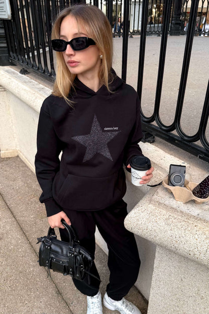 Sweat GLITZ noir brodé argenté, hoodie femme tendance avec motif étoile. Coton ringspun, polyester recyclé et poche téléphone intégrée. Style chic & confortable.